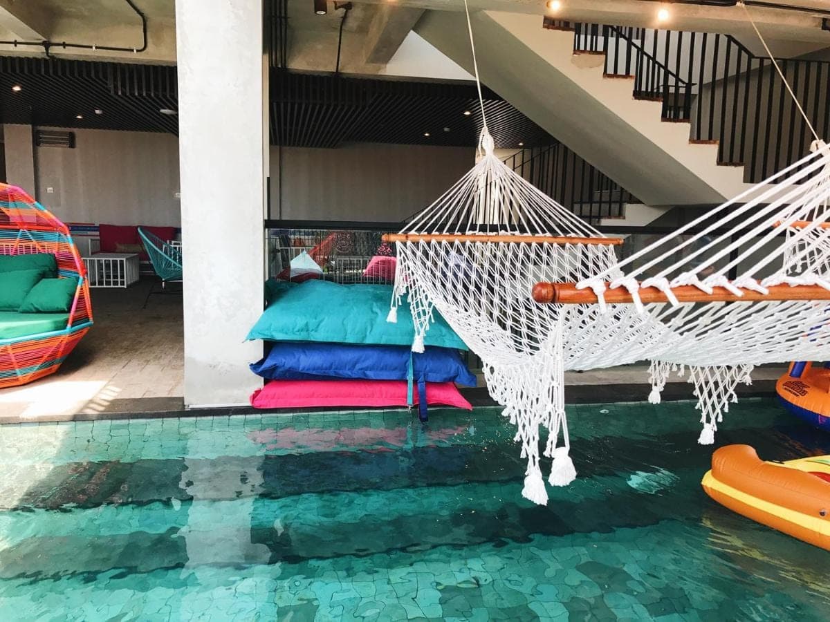 a room with a hammock and a swimming pool at Cara Cara Inn in Kuta