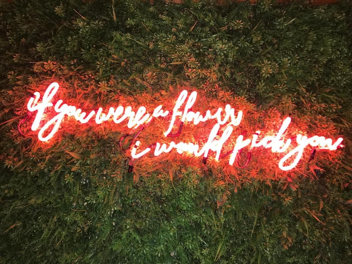 a neon sign that says happy holidays on the grass at Seahouse Bali Indah Beach Inn in Kuta