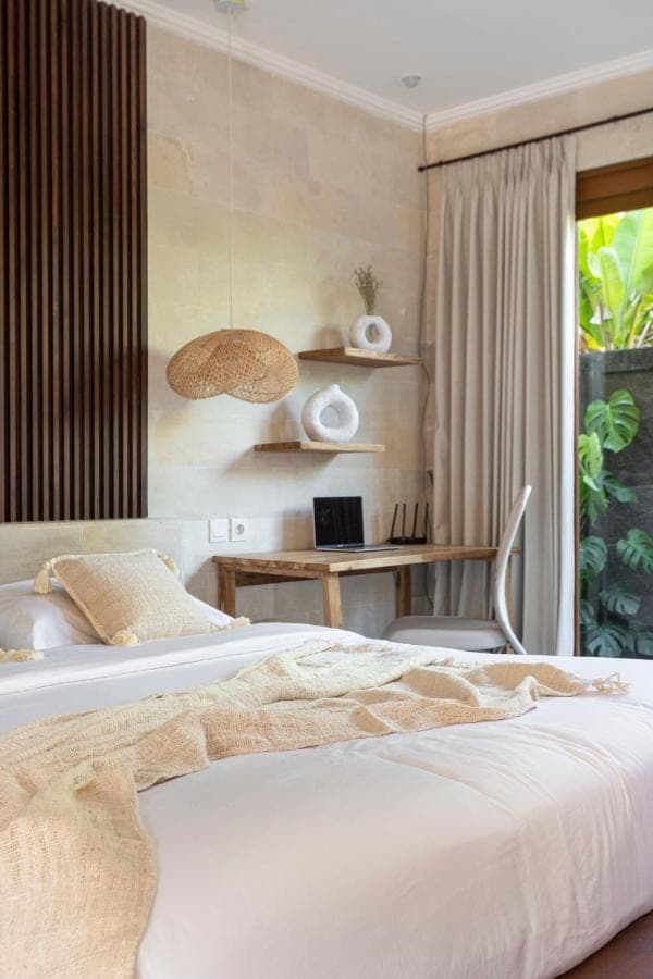 a bedroom with a bed and a desk with a laptop at Designer Studio Emy Sanur in Sanur