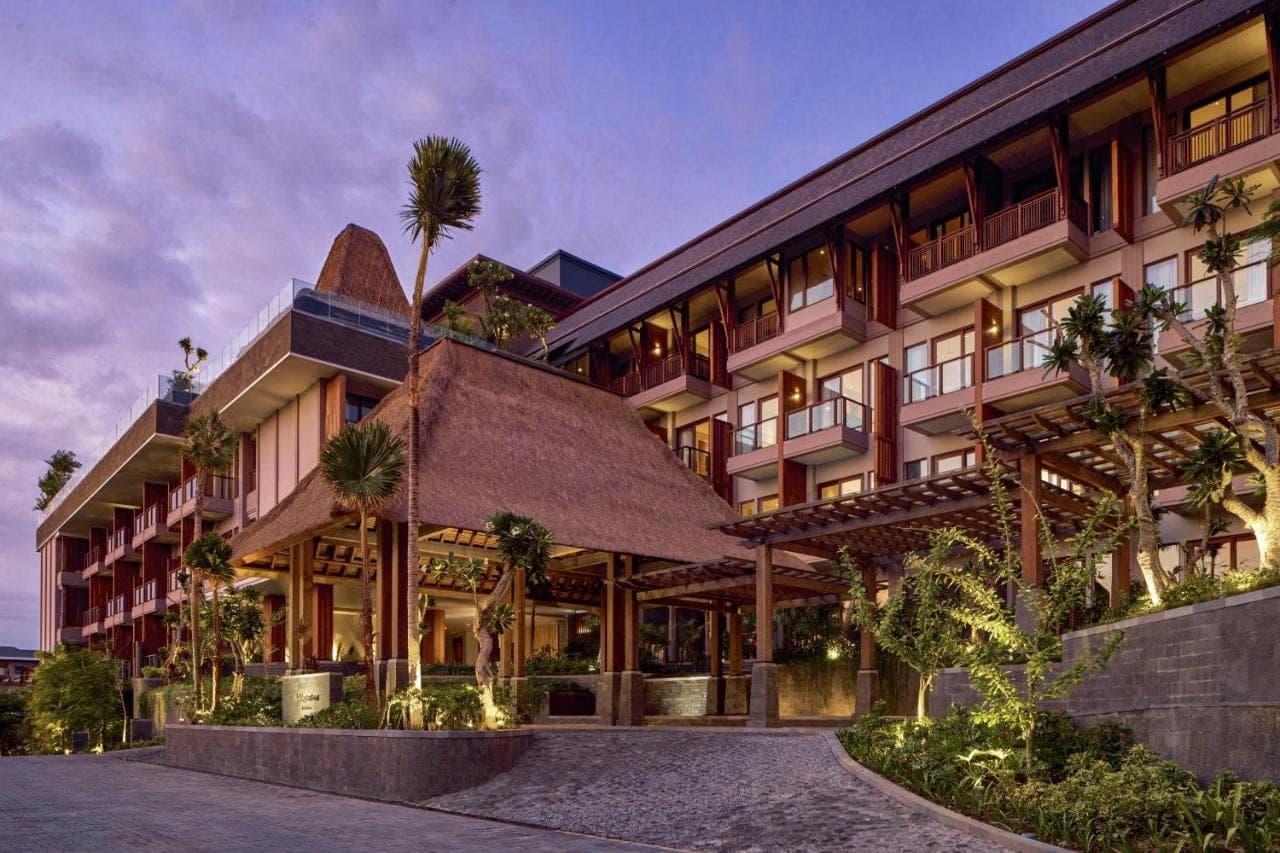 an exterior view of a building with palm trees at Holiday Inn Resort Bali Canggu by IHG in Canggu