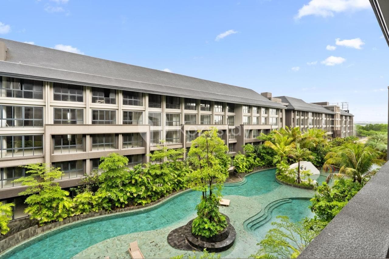 an apartment building with a pool in front of it at Rivana by Kozystay - Nusa Dua in Nusa Dua