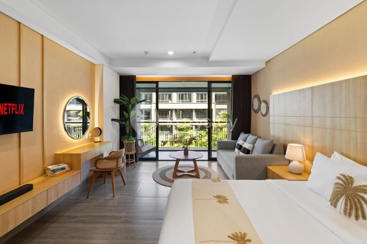 a hotel room with a bed and a living room at Rivana by Kozystay - Nusa Dua in Nusa Dua