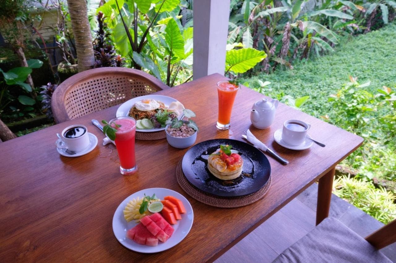 a wooden table with plates of food and drinks on it at Villa Ubud Sunshine in Ubud