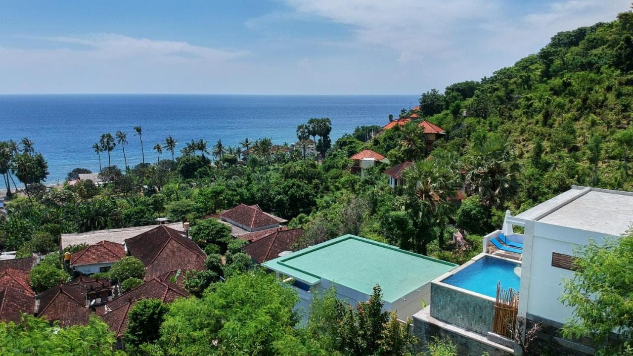 an aerial view of a resort with a swimming pool and the ocean at Villa Aska in Amed