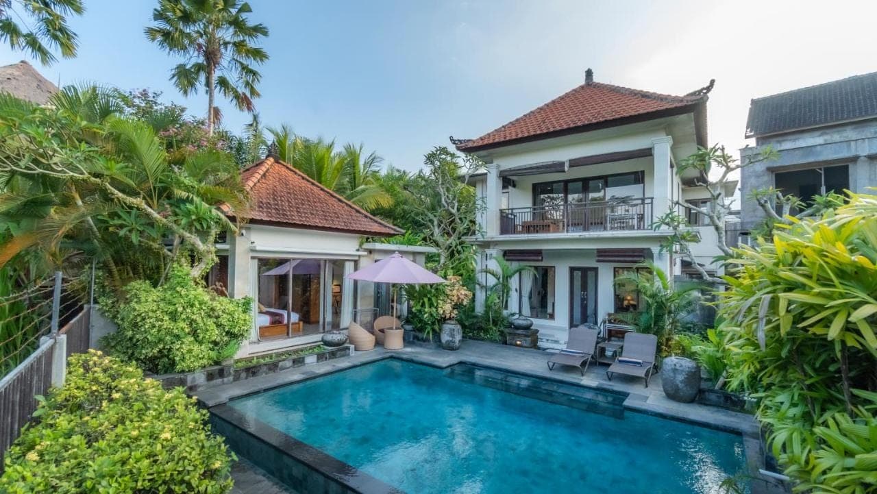 a villa with a swimming pool in front of a house at Bendito Ubud in Ubud
