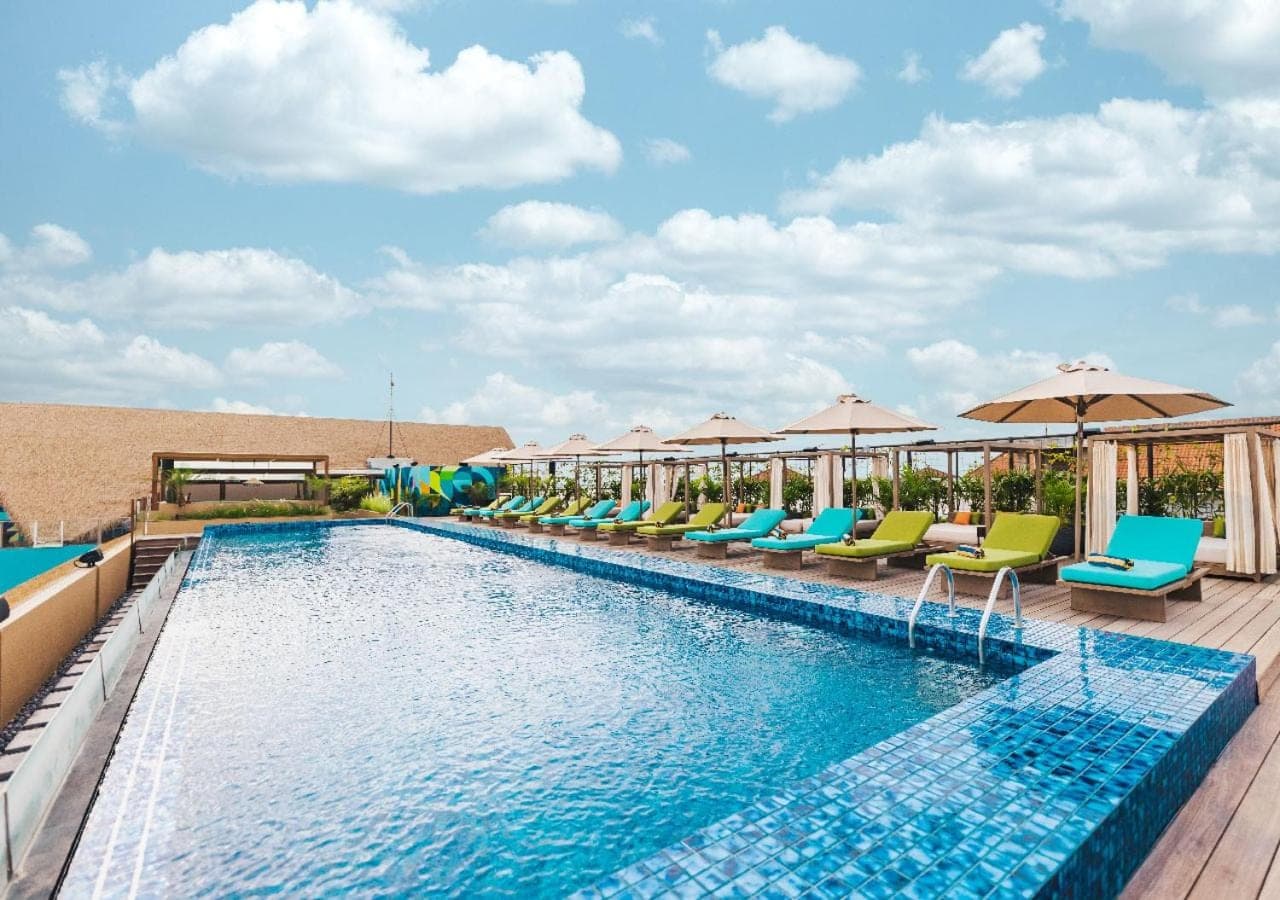 a swimming pool with chairs and umbrellas on a resort at MAMAKA Bali in Kuta