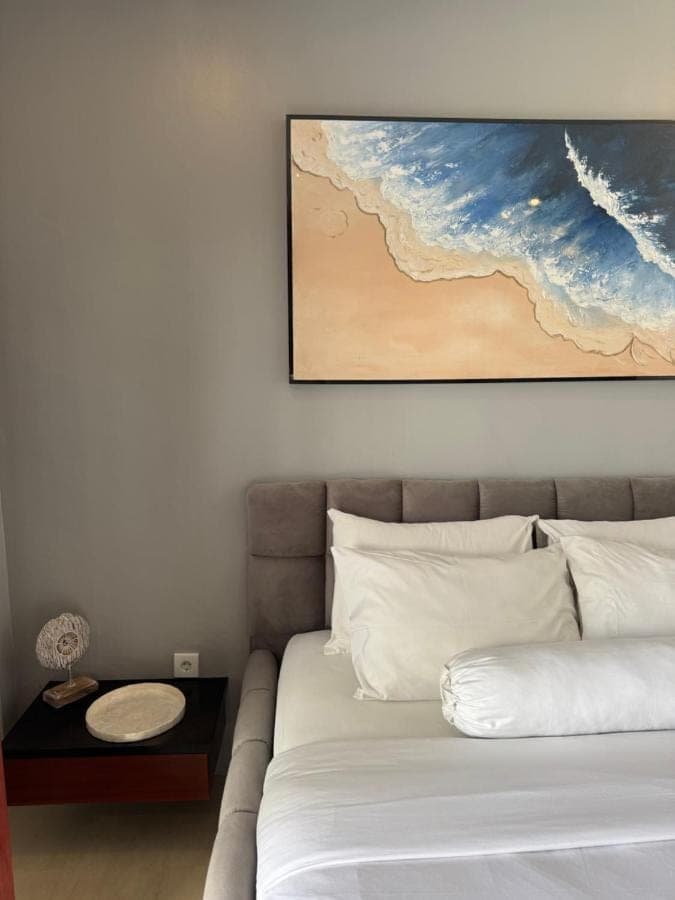a bedroom with a bed and a painting on the wall at Uluwatu Stay's Standard Room #1 in Uluwatu