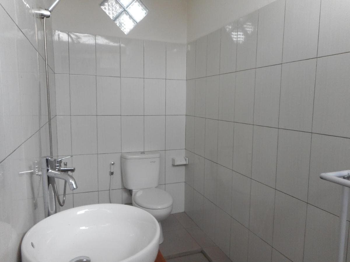 a white bathroom with a toilet and a sink at New Lilastana Homestay in Sidemen