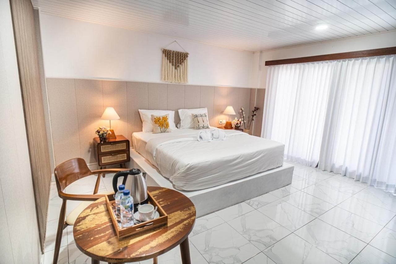 a hotel room with a bed and a table and chairs at Pondok Bingin Guest House in Uluwatu