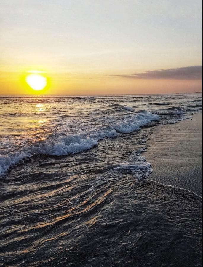 a sunset on the beach with the ocean at Grand Balisani Suites Hotel in Seminyak