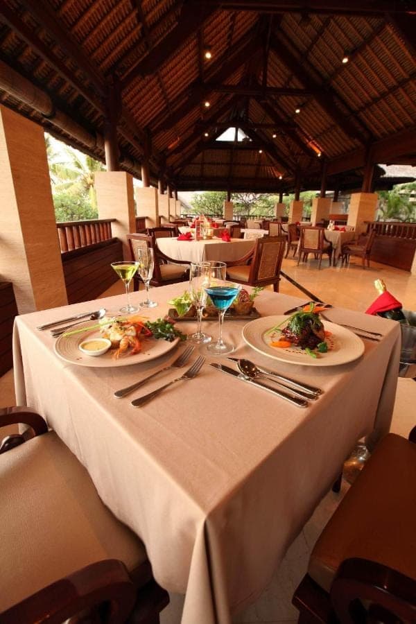 a table with plates of food and wine glasses on it at Grand Balisani Suites Hotel in Seminyak