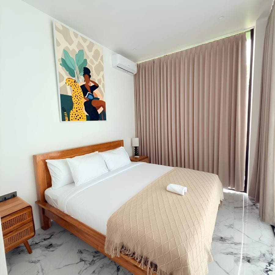 a bedroom with a bed and a painting on the wall at Sun on The Hill By Betterplace in Nusa Dua