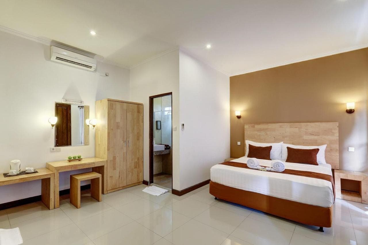 a bedroom with a large bed and a bathroom at Nipuri Resort and Villas Seminyak in Seminyak