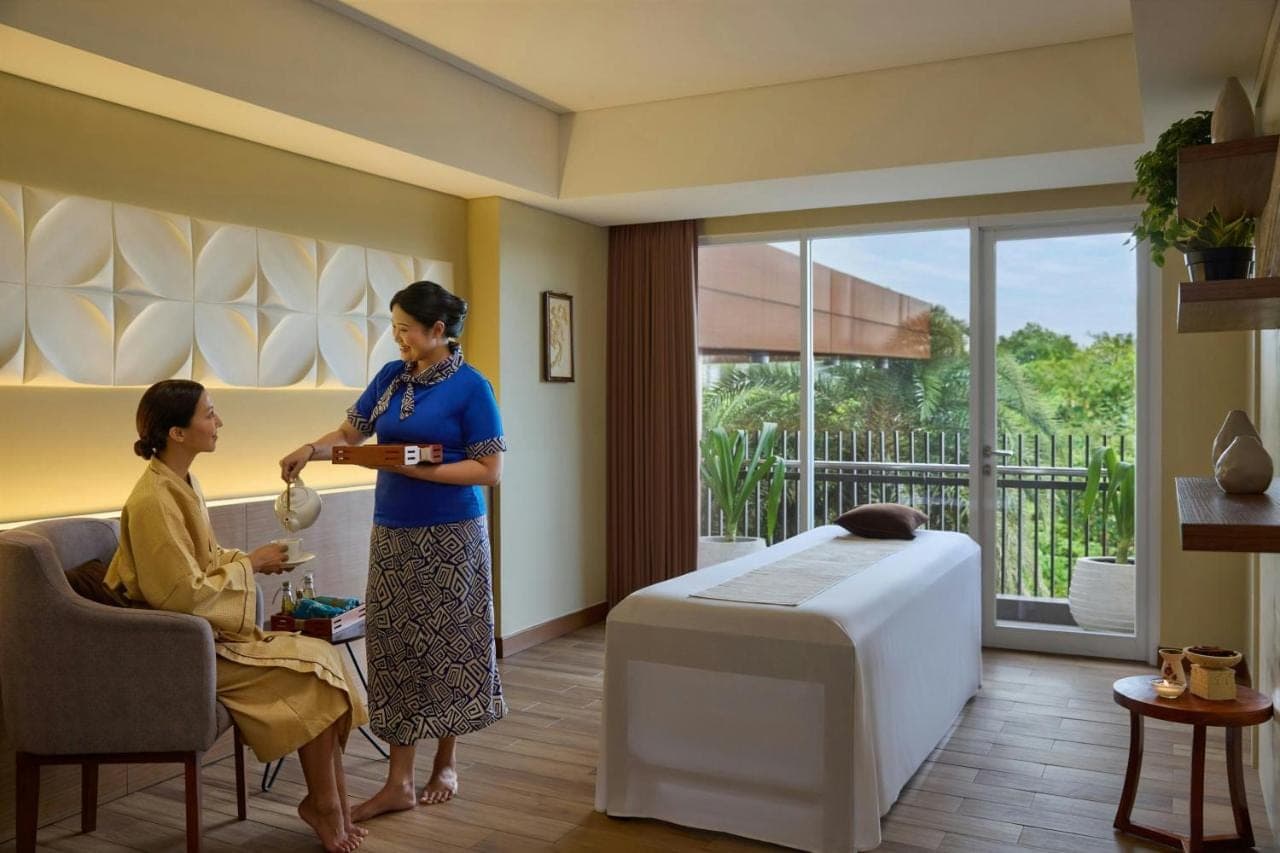a woman standing in a living room with a woman sitting in a chair at Fairfield by Marriott Bali Kuta Sunset Road in Kuta