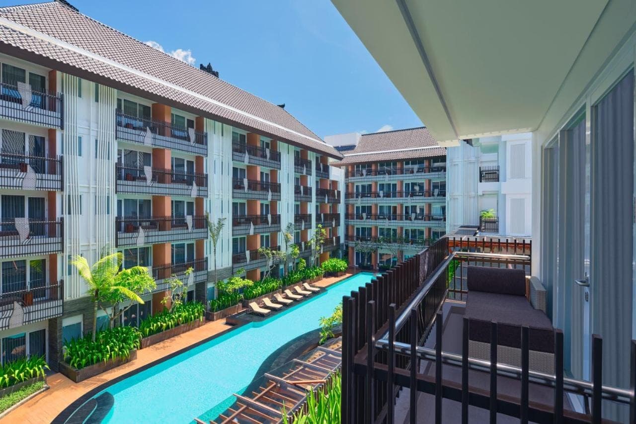 an apartment building with a swimming pool and a balcony at Fairfield by Marriott Bali Kuta Sunset Road in Kuta
