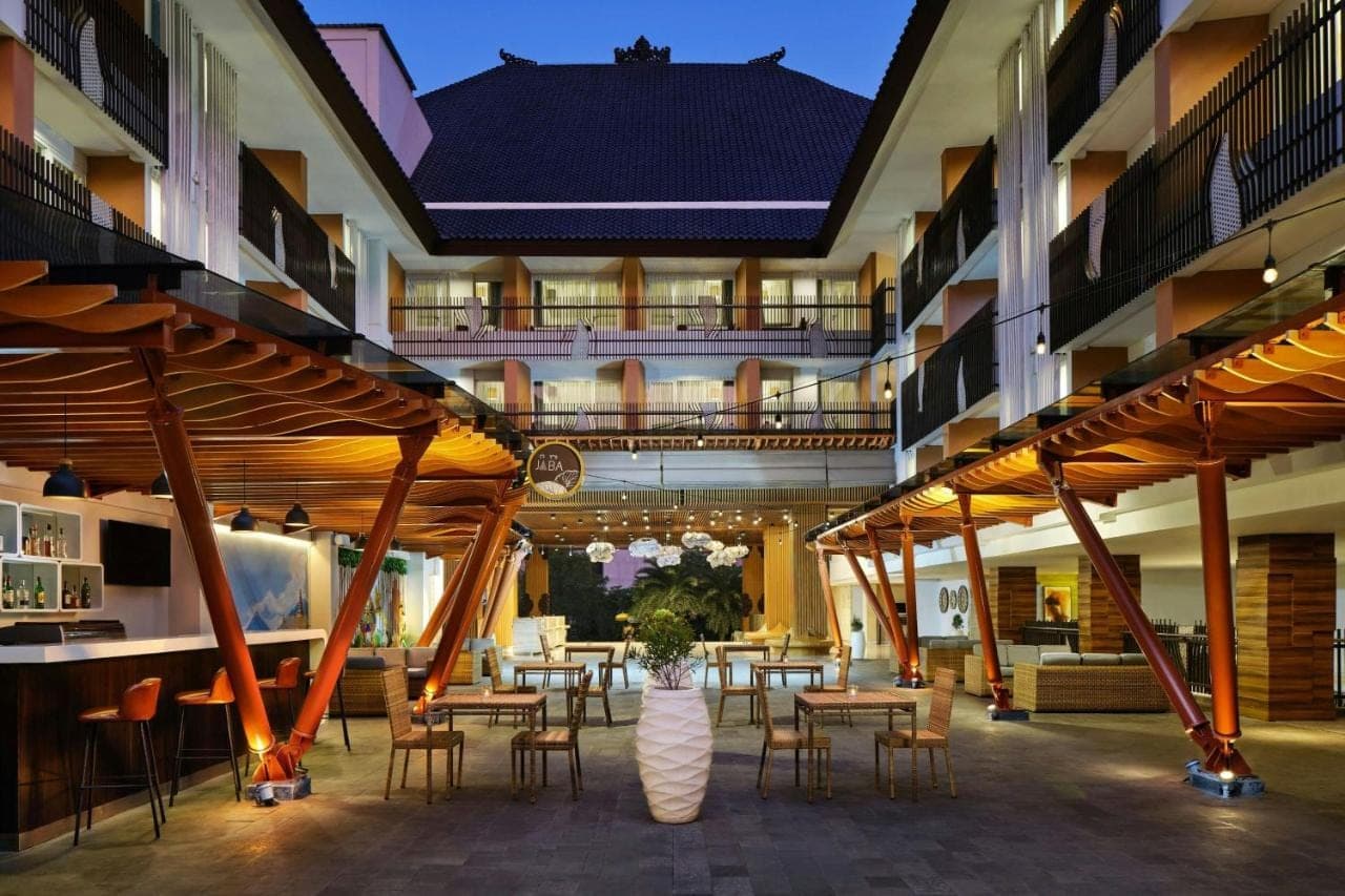 a restaurant with tables and chairs in a building at Fairfield by Marriott Bali Kuta Sunset Road in Kuta