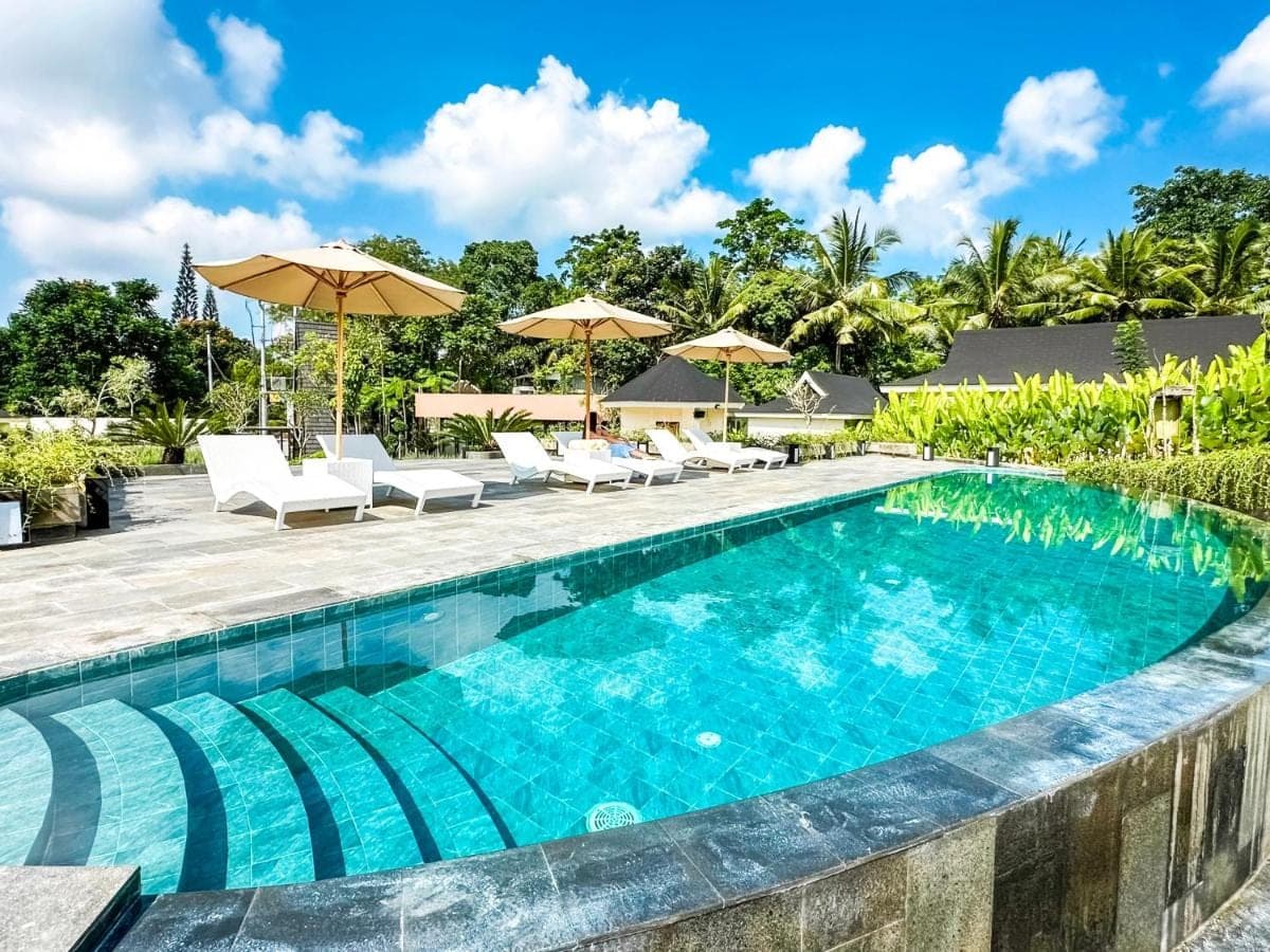 a swimming pool at a resort with chairs and umbrellas at Tanada Resort Ubud by Amithya - Brand New Opened 2026 in Ubud
