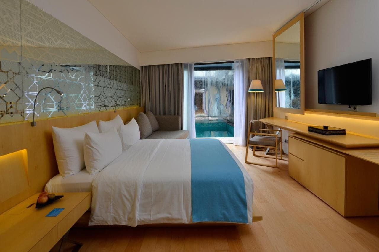 a hotel room with a large bed and a television at IZE Seminyak by LifestyleRetreats in Seminyak