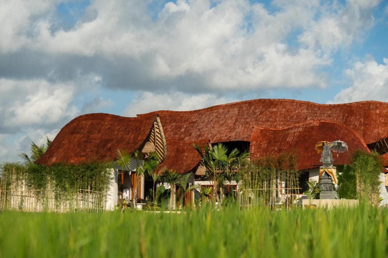 a building with a rusty roof and some grass at Bamboo Layang Boutique Hotel, Rice Fields - Ubud in Ubud