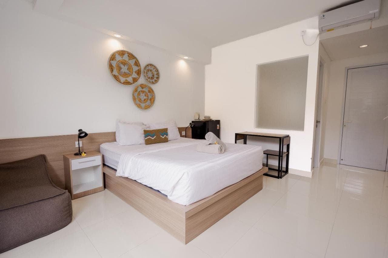 a white bedroom with a bed and a couch at Homely Bali at Rajapala in Seminyak