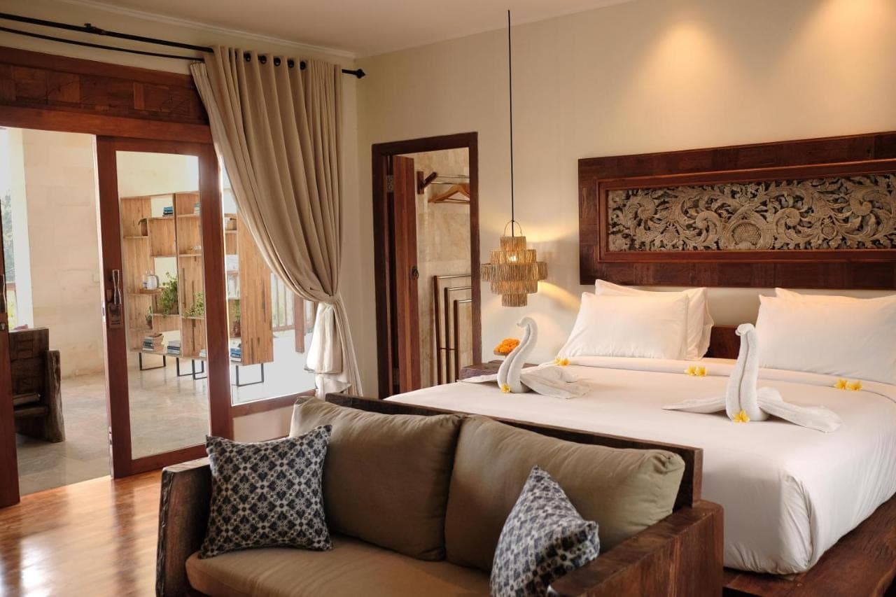 a hotel room with a bed and a couch at Sri Ratih Cottages, CHSE Certified in Ubud
