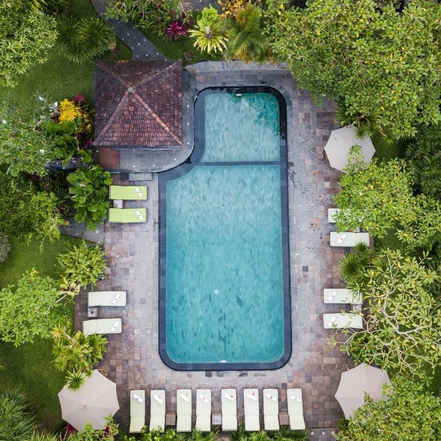 an overhead view of a swimming pool with chairs and plants at Sri Ratih Cottages, CHSE Certified in Ubud