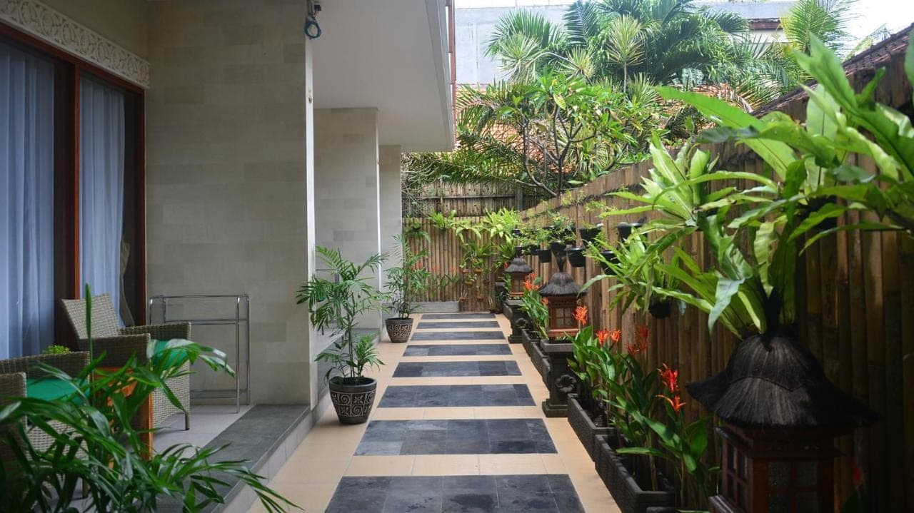 a hallway with potted plants in a building at Puri Kesari Guest House in Sanur