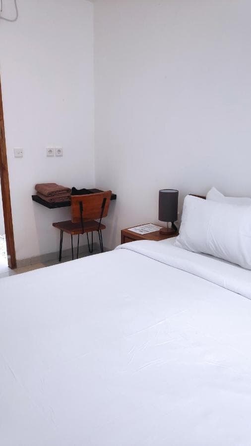 a bedroom with a white bed and a desk at NOKA ULUWATU BED And BREAKFAST in Uluwatu