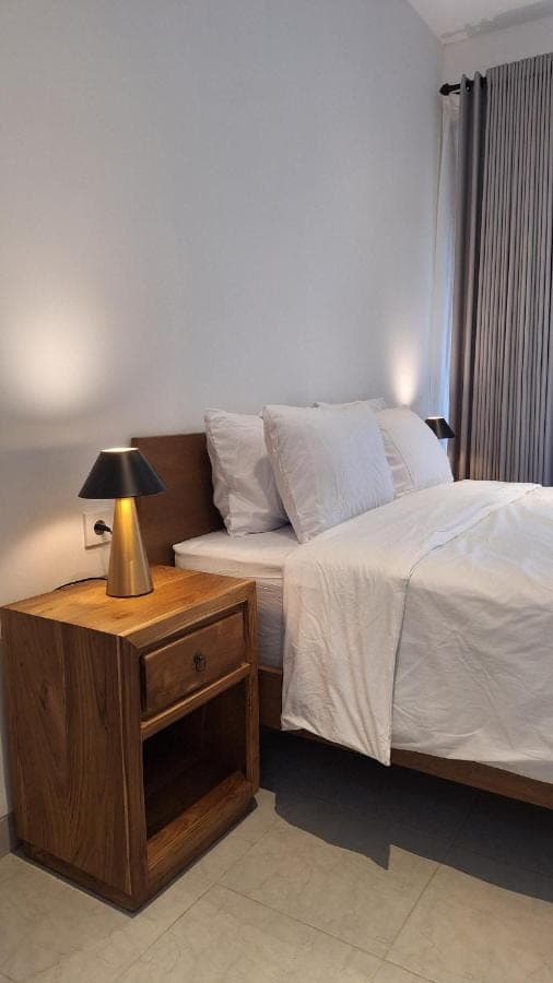 a bedroom with a bed and a lamp on a night stand at NOKA ULUWATU BED And BREAKFAST in Uluwatu