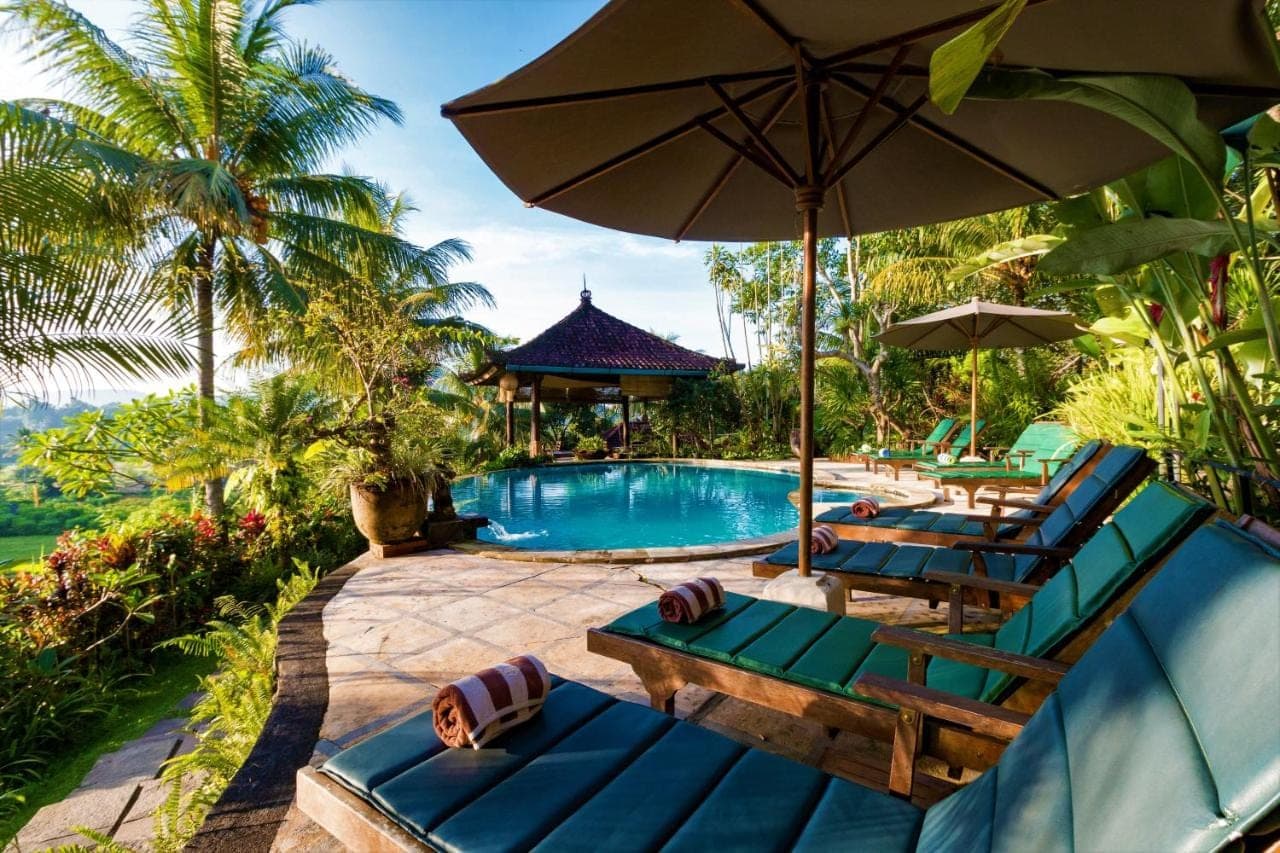 a swimming pool with two lounge chairs and an umbrella at Cepik Villa Sidemen by AGATA in Sidemen