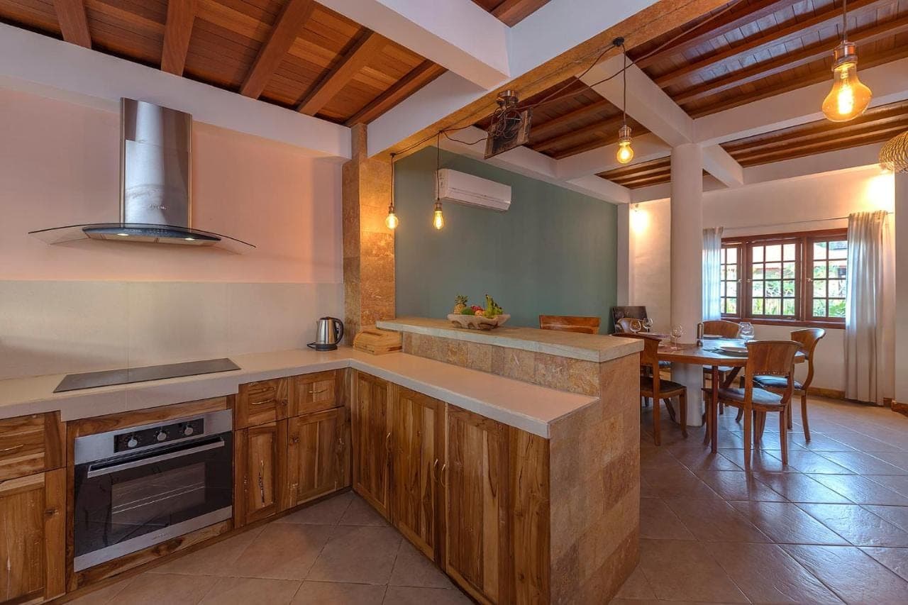 a kitchen with wooden cabinets and a dining room at Rose Valley Villa in Amed