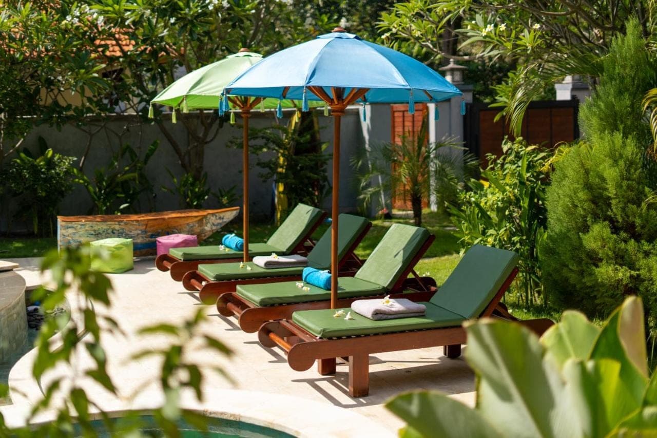 a row of lounge chairs with an umbrella at Rose Valley Villa in Amed