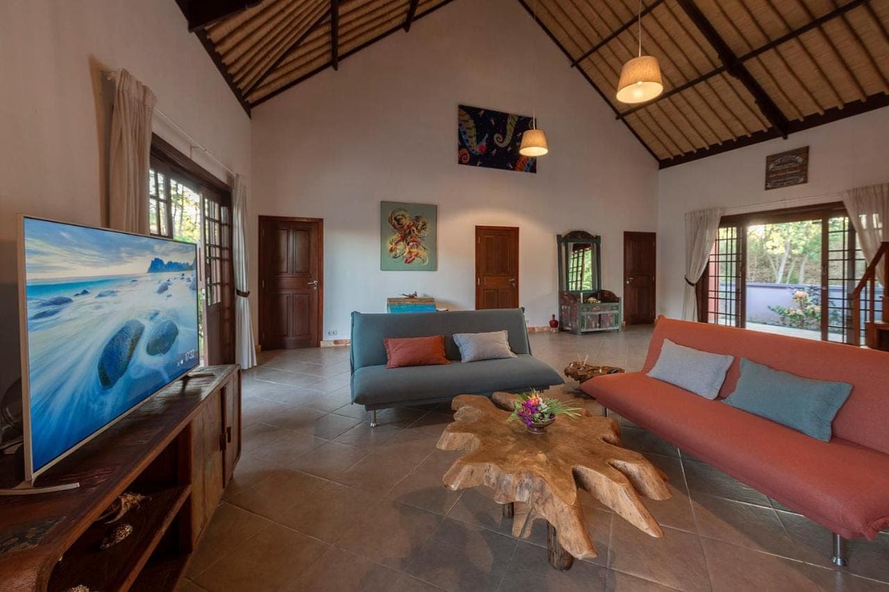 a living room with a tv and a couch and a table at Rose Valley Villa in Amed