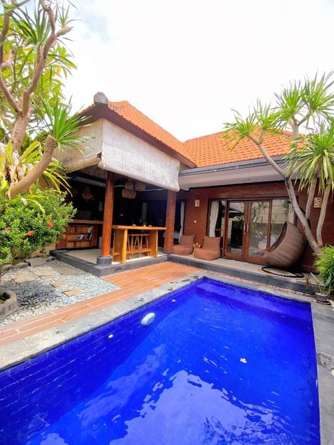 a large blue swimming pool in front of a house at Nita Villa Bali in Canggu
