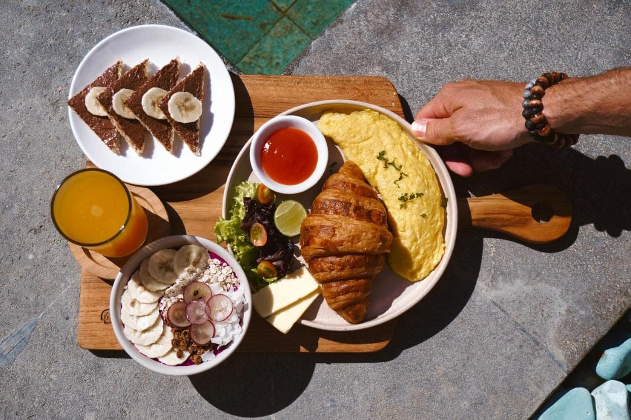 a wooden table with plates of food on it at Leafy Home Canggu - 5 Mins Walk to Echo Beach in Canggu
