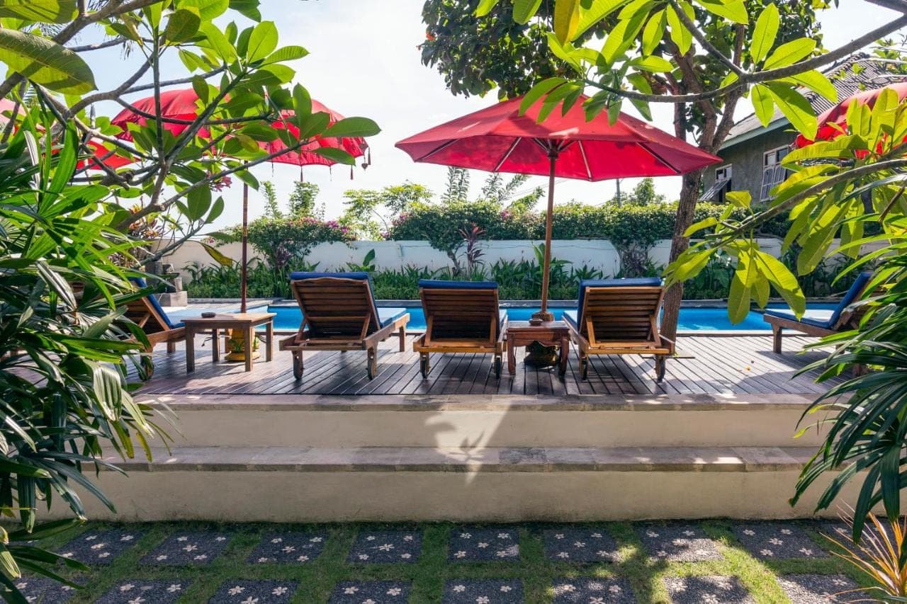 a patio with chairs and umbrellas next to a pool at Waroeng Surya Home Stay in Uluwatu