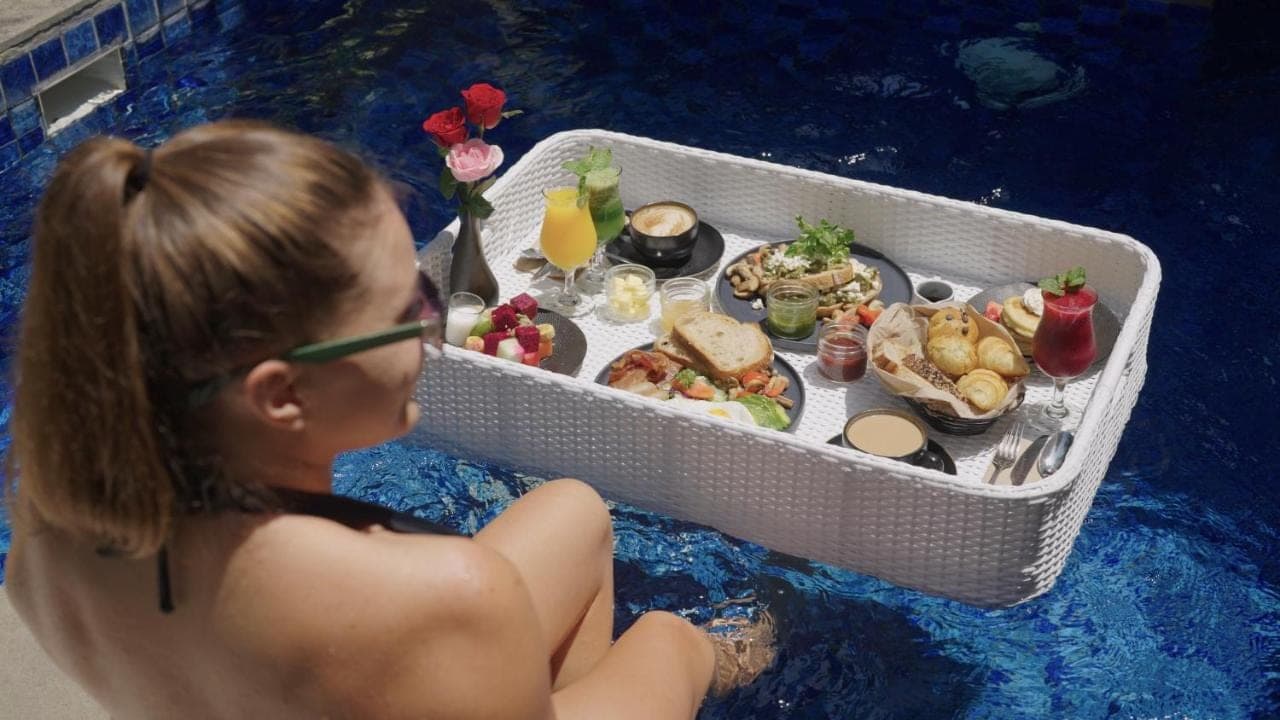 a woman sitting in front of a table of food at The Vira Bali Boutique Hotel & Suite in Kuta