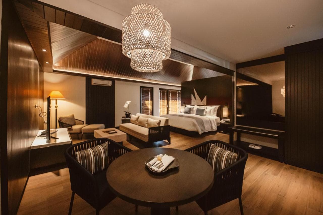 a hotel room with a bed and a living room at The Vira Bali Boutique Hotel & Suite in Kuta