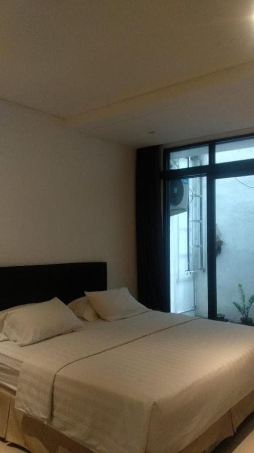 a bedroom with a large white bed with a window at 21 Lodge in Nusa Dua