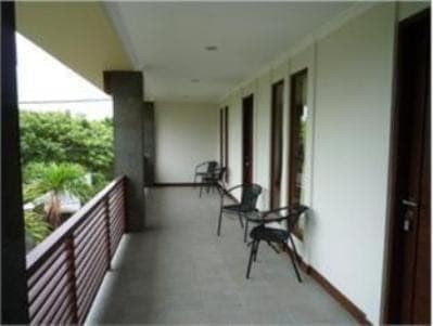 a balcony with chairs and tables on a building at 21 Lodge in Nusa Dua