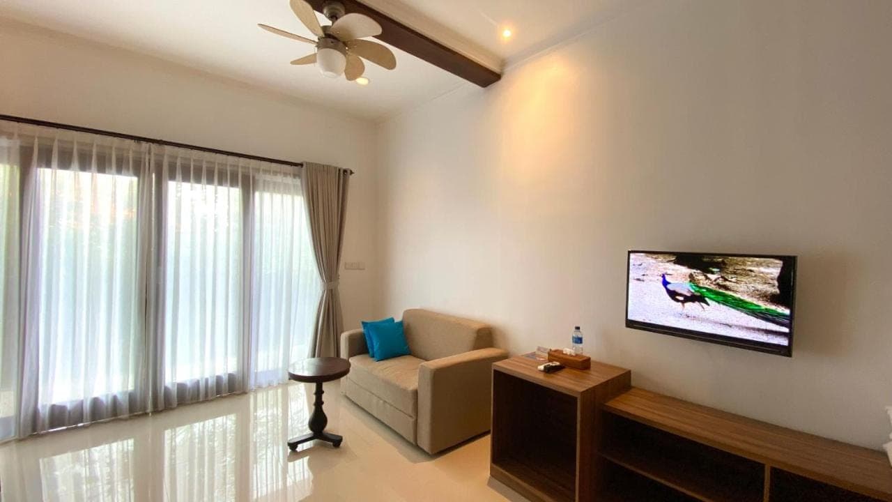 a living room with a couch and a tv on the wall at Mandox Bali Homestay in Nusa Dua