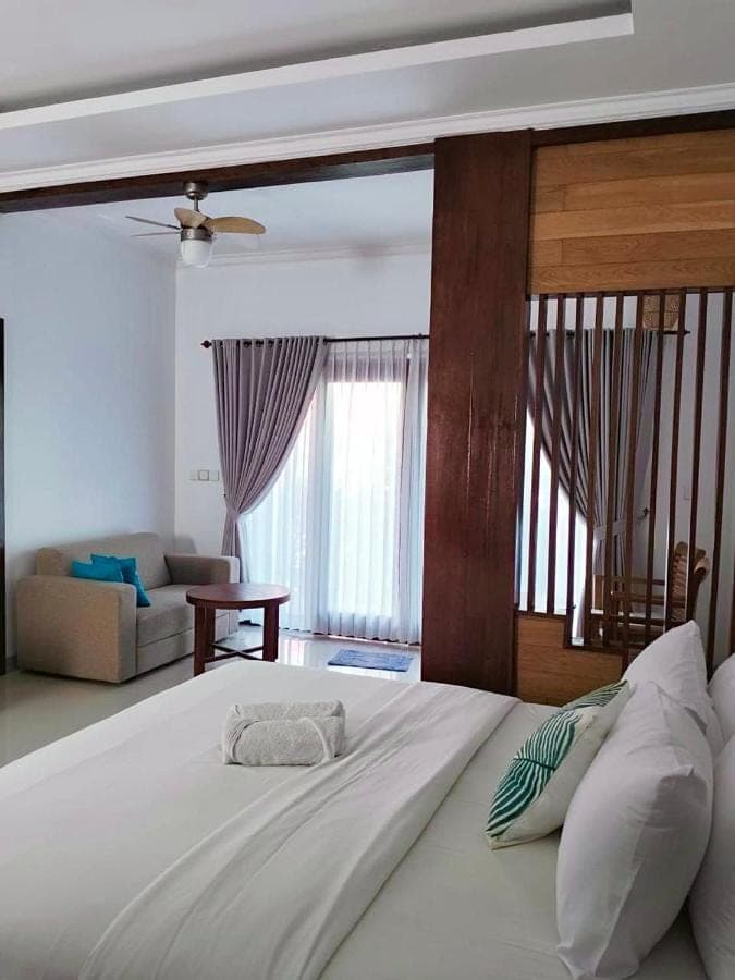a large white bed in a room with a couch at Mandox Bali Homestay in Nusa Dua