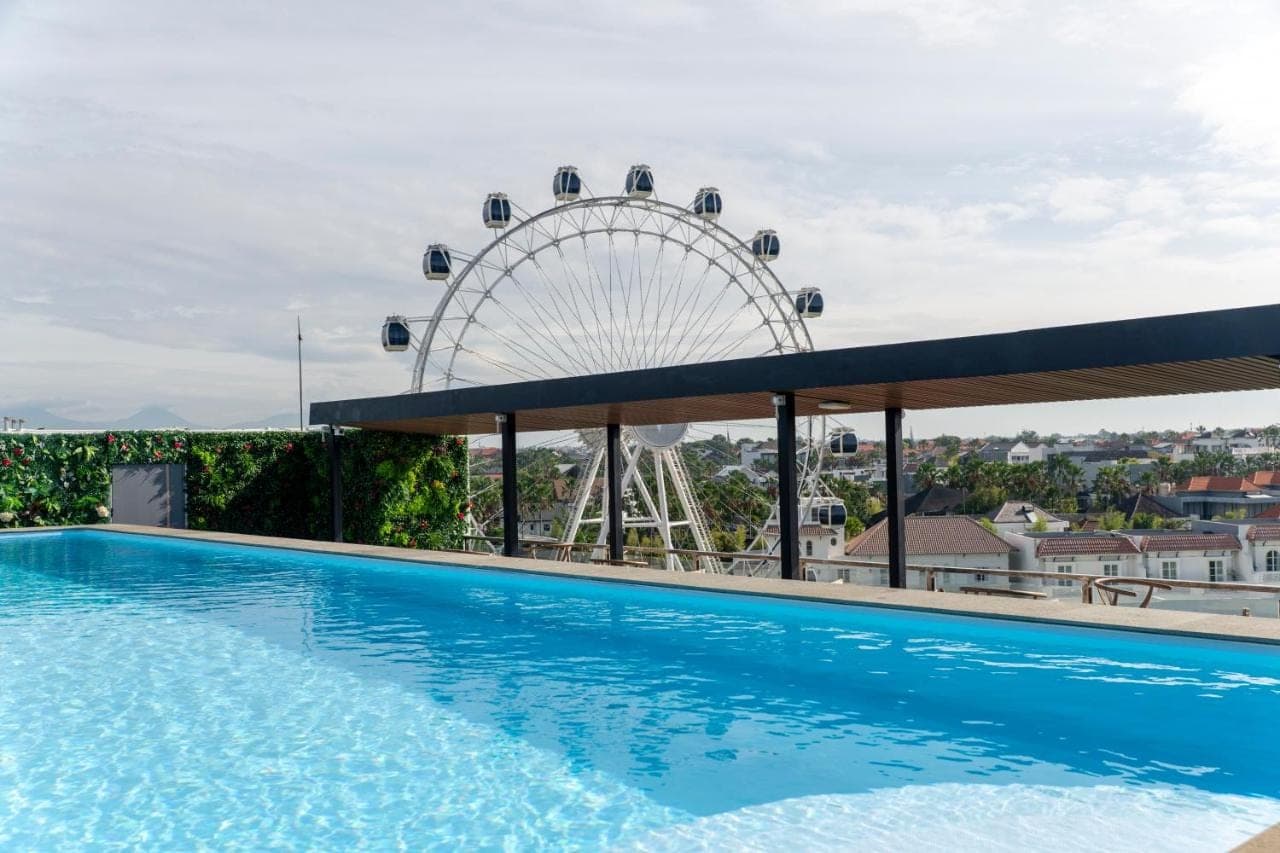 a swimming pool with a ferris wheel in the background at JJ JIVANA Bali in Canggu