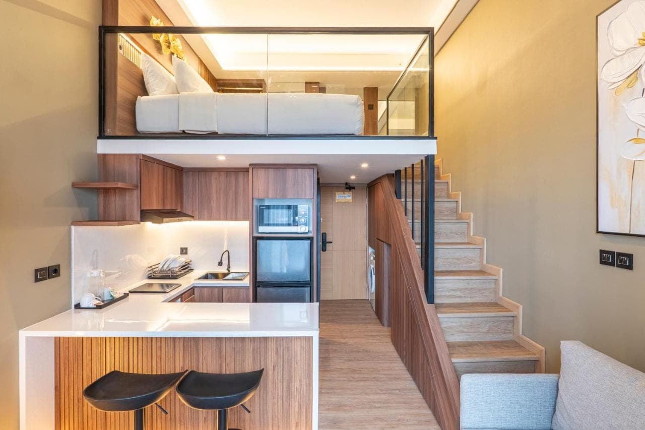 a small apartment with a staircase leading up to a bedroom at JJ JIVANA Bali in Canggu