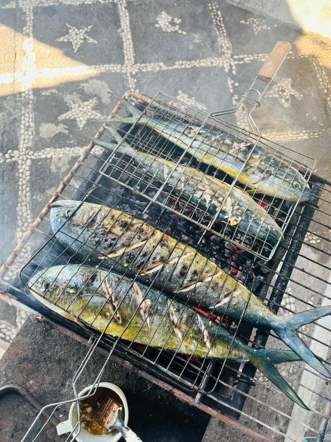 two racks of fish cooking on a grill at Tradisi Villas in Amed