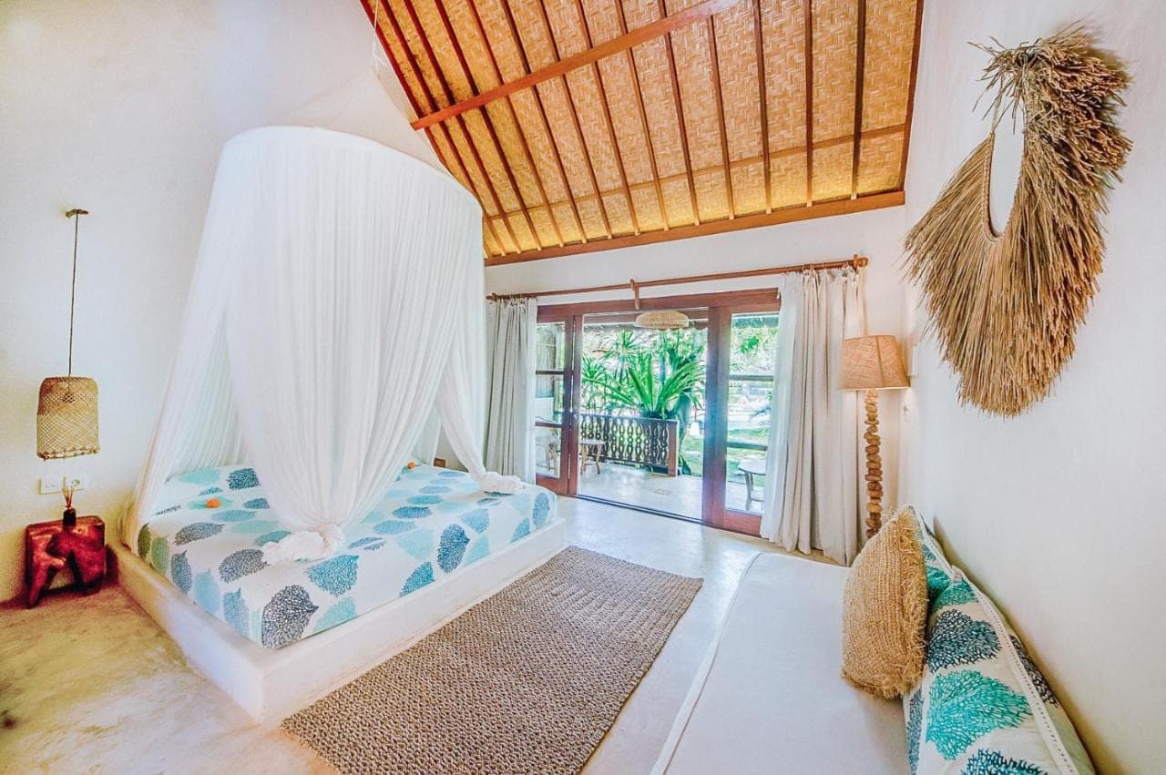 a bedroom with a bed with a mosquito net at Mule Malu in Uluwatu