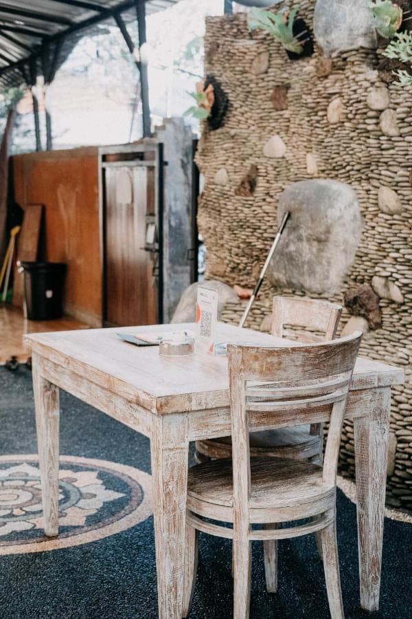 a wooden table and a chair with a laptop on it at Kubu Indah Homestay Sanur in Sanur