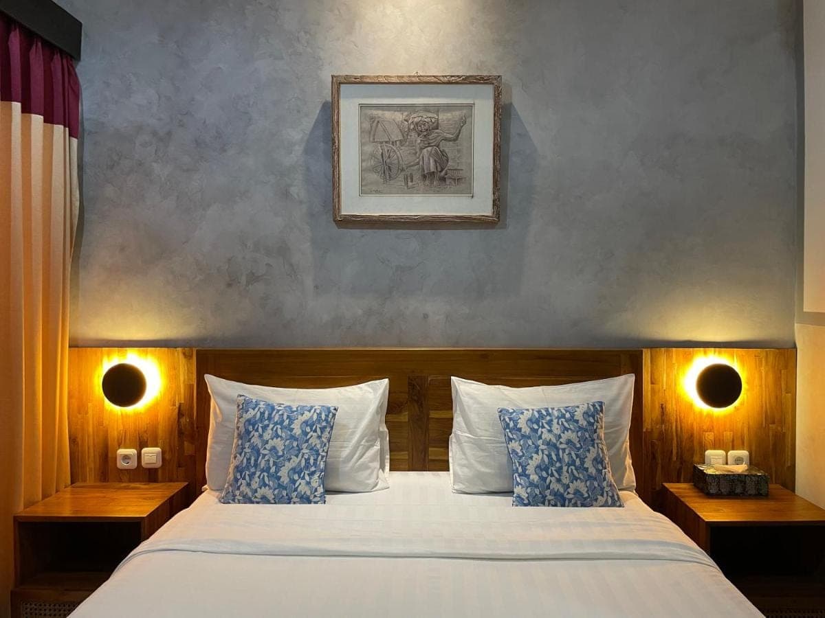 a bedroom with a bed with blue and white pillows at Kubu Indah Homestay Sanur in Sanur
