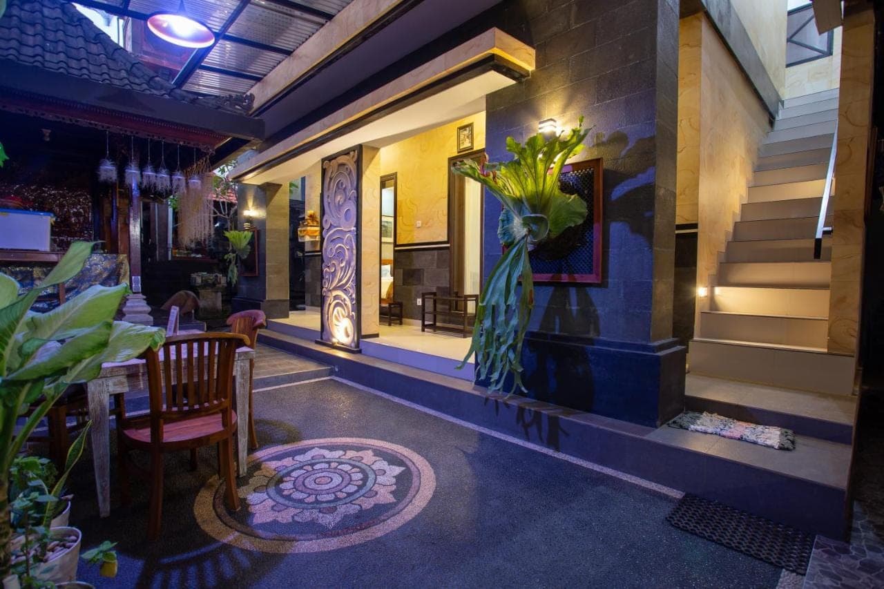 a dining room with a table and a vase of flowers at Kubu Indah Homestay Sanur in Sanur