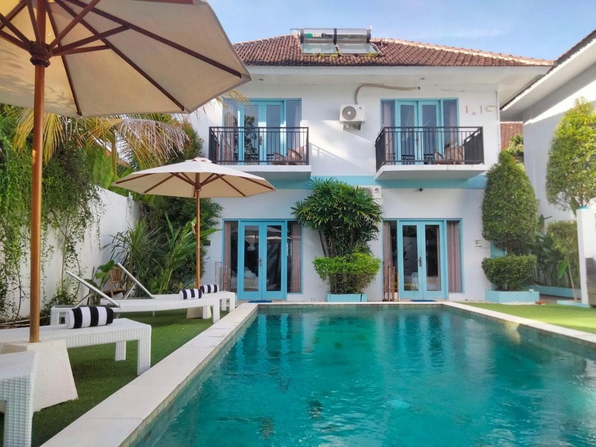 a villa with a swimming pool and a house at Gatsby Hotel Hostel in Uluwatu
